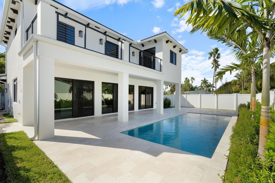 View of the back of this beautifully designed home.  You can see the large balcony. Generous sized pool and deck area along with walls of screened sliders bringing the outdoors to the inside.