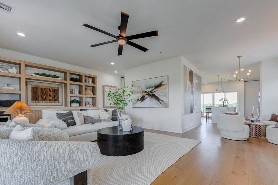 This stunning open living area features a beautifully designed built-in shelving unit that adds both style and functionality. Perfect for displaying décor, books, or personal touches, it creates a sophisticated focal point in the room. The spacious layout, combined with soft natural lighting and warm finishes, makes this area both comfortable and visually appealing. The picture shown is from the model home with the same floor plan, Rev floor plan.