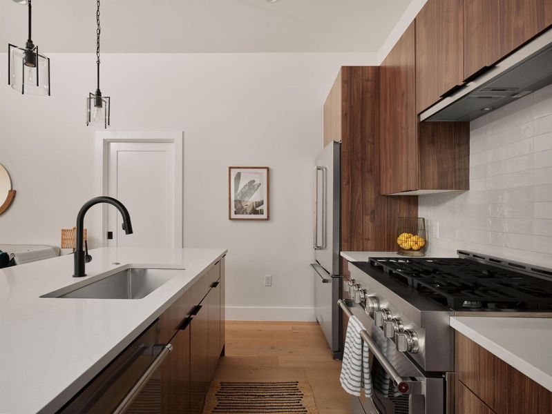 Kitchen featuring modern cabinets, high end appliances, light wood finished floors, and range hood Kitchen featuring modern cabinets, high end appliances, light wood finished floors, and range hood