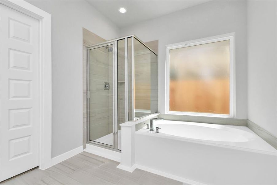 The primary en-suite has a soaking tub to give you that spa experience. The large privacy window allow lots of nature light in the space. Sample photo of completed home with similar plan. As built color and selections may vary.