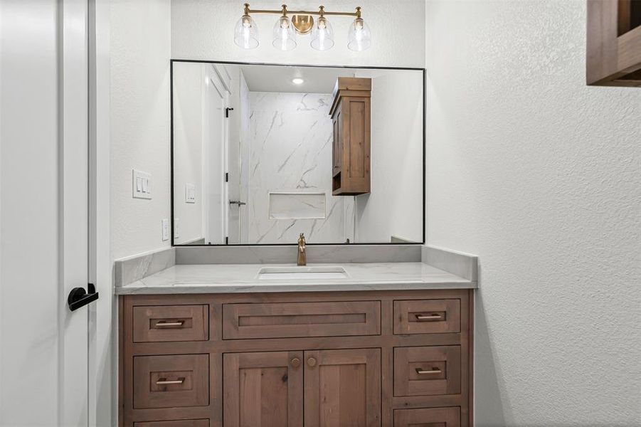 Half bathroom featuring a textured wall and vanity Half bathroom featuring a textured wall and vanity