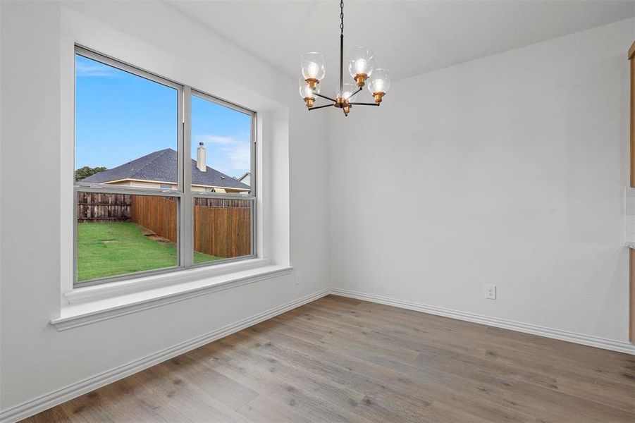 Empty room featuring an inviting chandelier and light hardwood / wood-style flooring