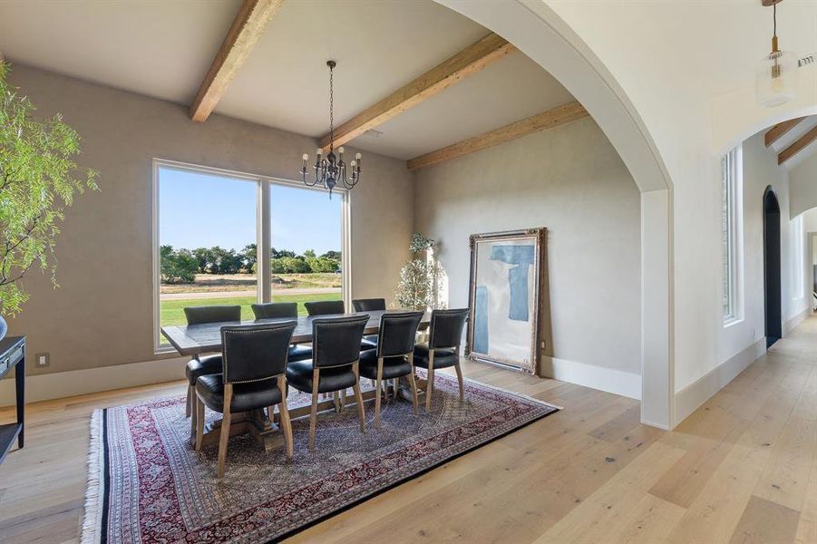 Dining room with beam ceiling, light hardwood / wood-style floors, and a chandelier