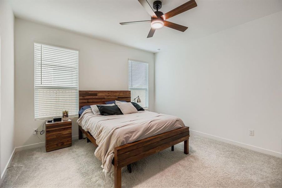 Bedroom featuring multiple windows, light carpet, and ceiling fan