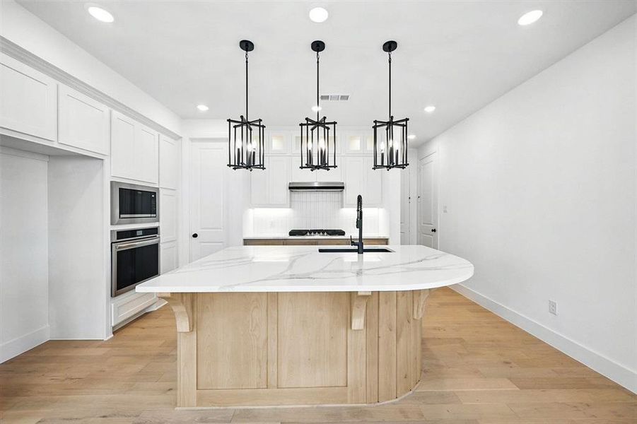 Kitchen with light wood finished floors, white cabinetry, decorative backsplash, appliances with stainless steel finishes, and recessed lighting Kitchen with light wood finished floors, white cabinetry, decorative backsplash, appliances with stainless steel finishes, and recessed lighting