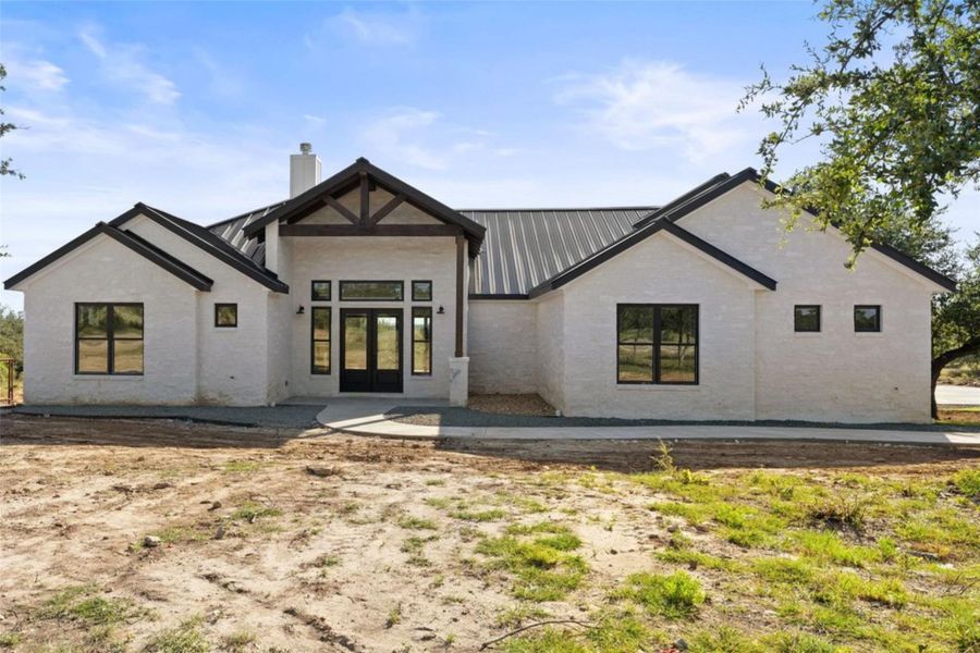 A newly constructed modern farmhouse with a prominent gabled entry and striking metal roof. A newly constructed modern farmhouse with a prominent gabled entry and striking metal roof.