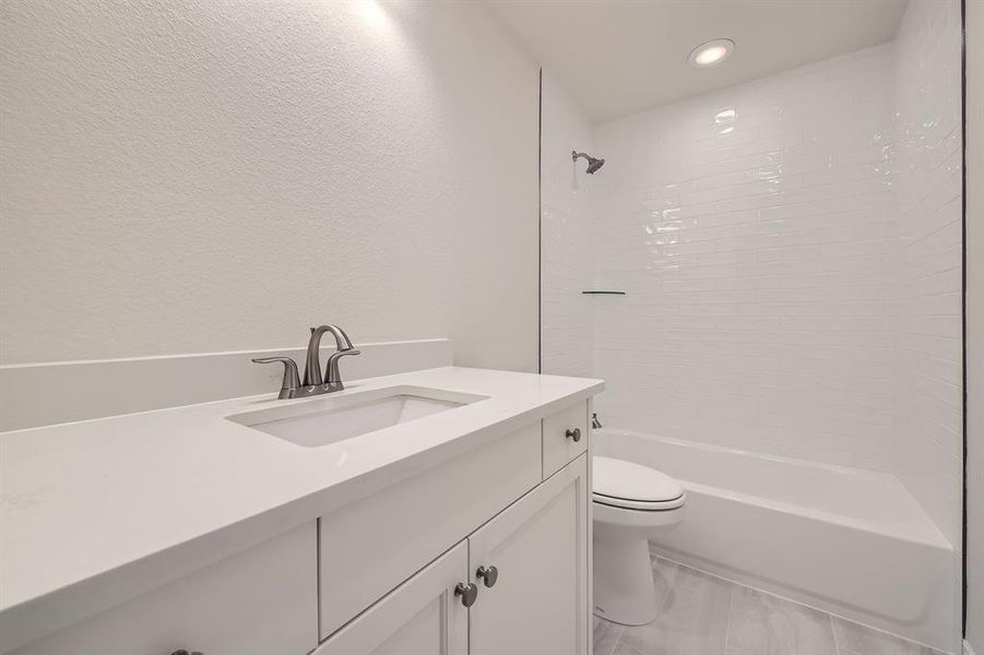 Full bathroom with toilet, vanity, and tiled shower / bath