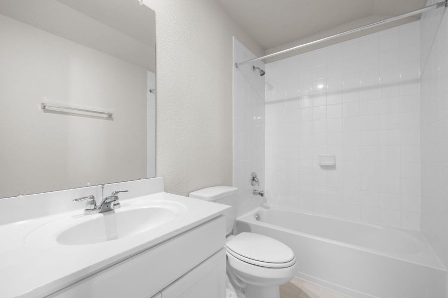 The secondary bath features tile flooring, white cabinetry and light countertops and a shower/tub combo. Perfect for accommodating any visiting family and friends.