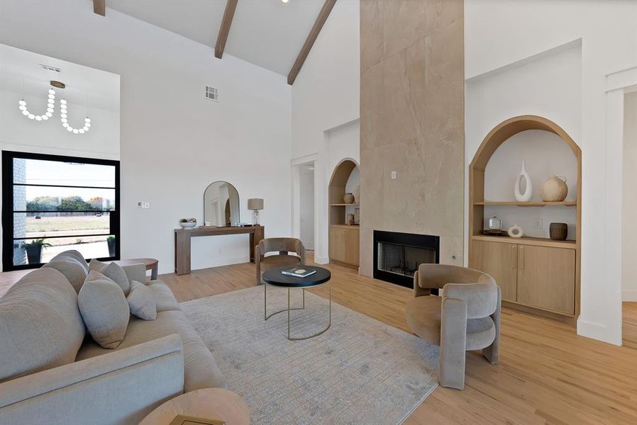 Living area featuring built in features, high vaulted ceiling, light wood finished floors, a fireplace, and beam ceiling