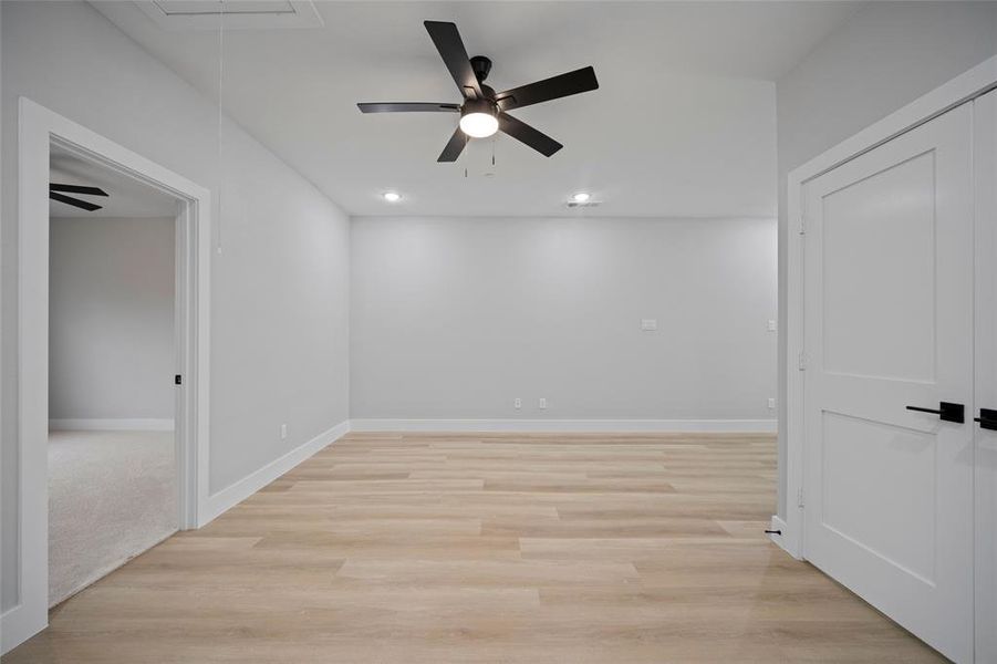 Empty room with light wood finished floors, recessed lighting, attic access, and baseboards