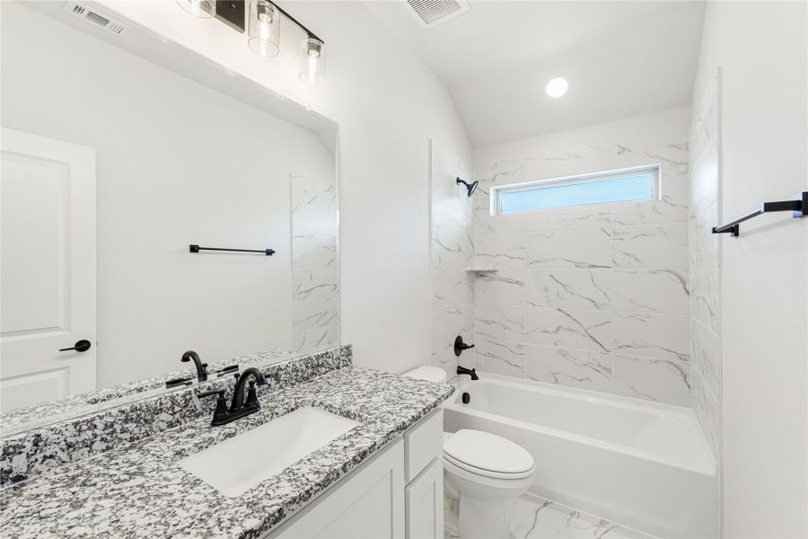 Bathroom with granite vanity, white cabinets, and tub-shower combo with marble-look tile surround