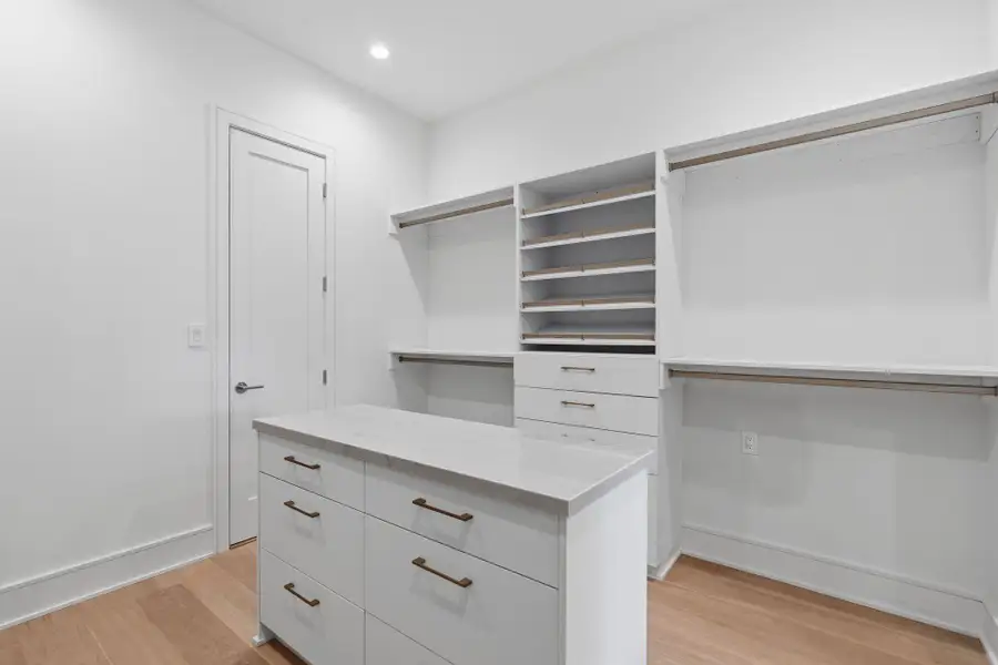 Custom closet system with stone-topped island and LED lighting system.