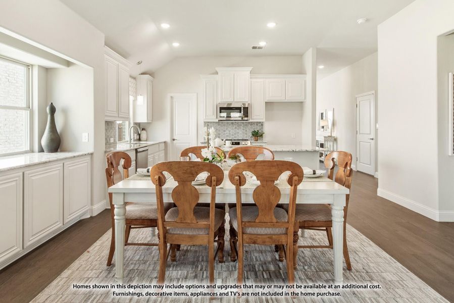 Dining area with white table and wood chairs open to kitchen with white cabinets and hardwood floors Dining area with white table and wood chairs open to kitchen with white cabinets and hardwood floors