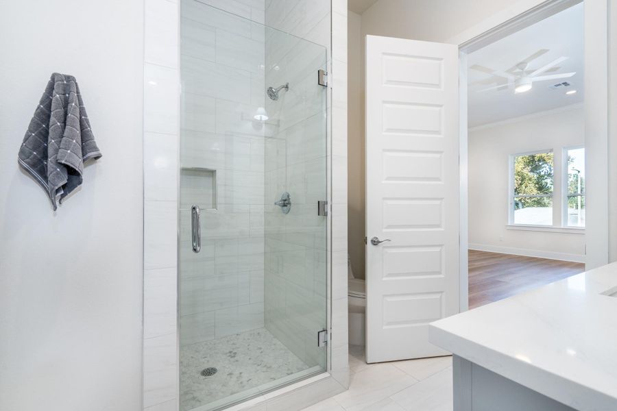 Modern bath with glass-enclosed shower, built-in niche, and sleek tile finishes. Modern bath with glass-enclosed shower, built-in niche, and sleek tile finishes.