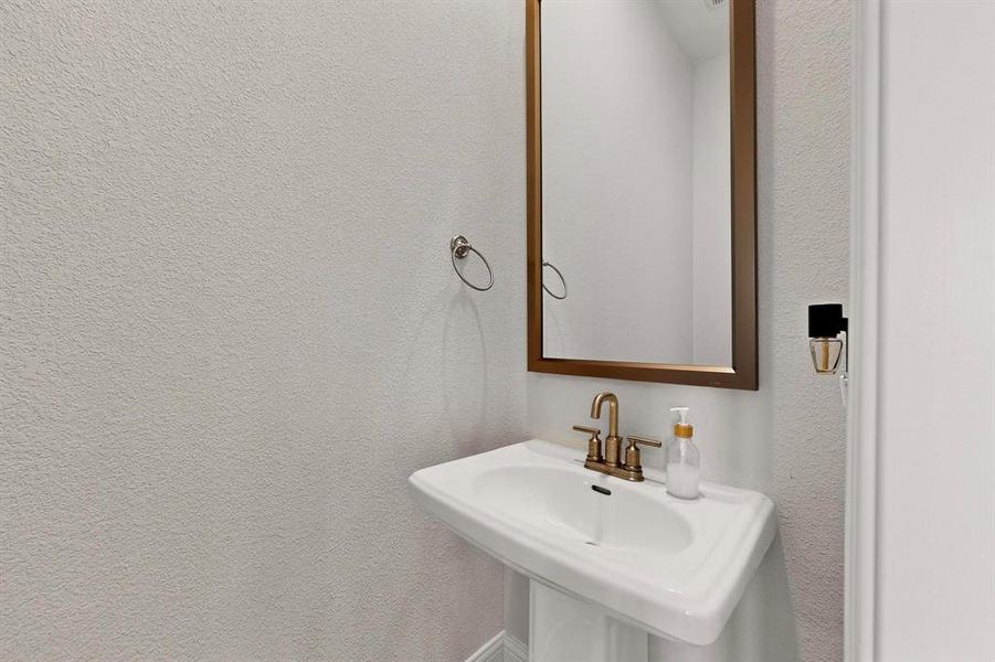 Bathroom featuring a sink and a textured wall Bathroom featuring a sink and a textured wall