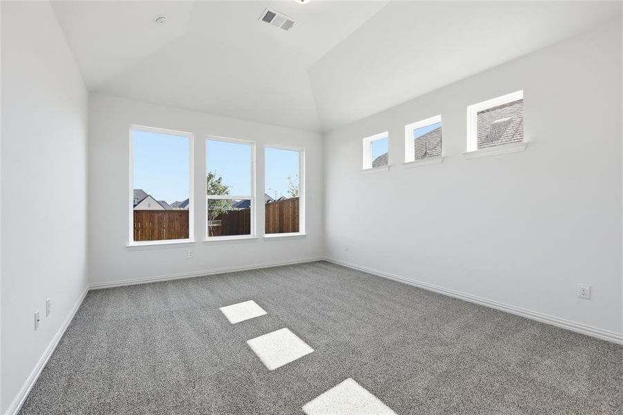 Carpeted spare room featuring vaulted ceiling and baseboards