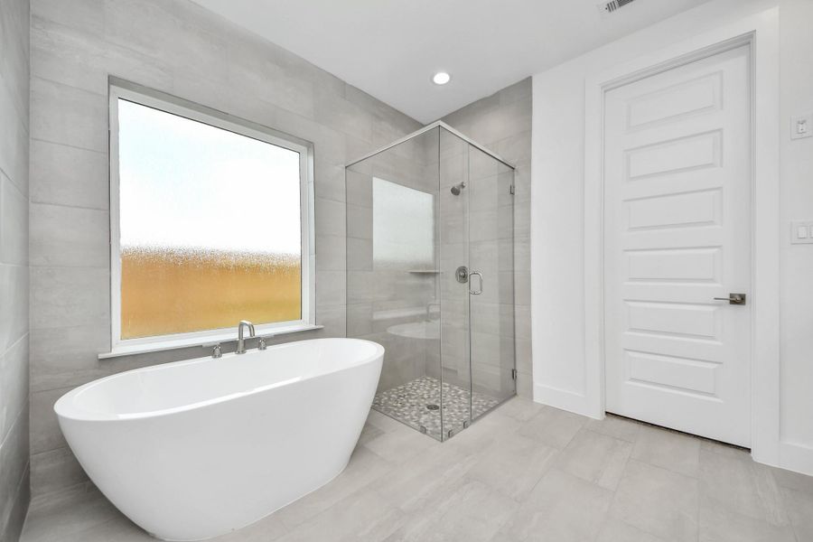 Indulge in a spa-like retreat within the confines of this primary bathroom. Delight in a spacious walk-in shower enveloped in stylish tile surround, unwind in a separate garden tub adorned with custom detailing.