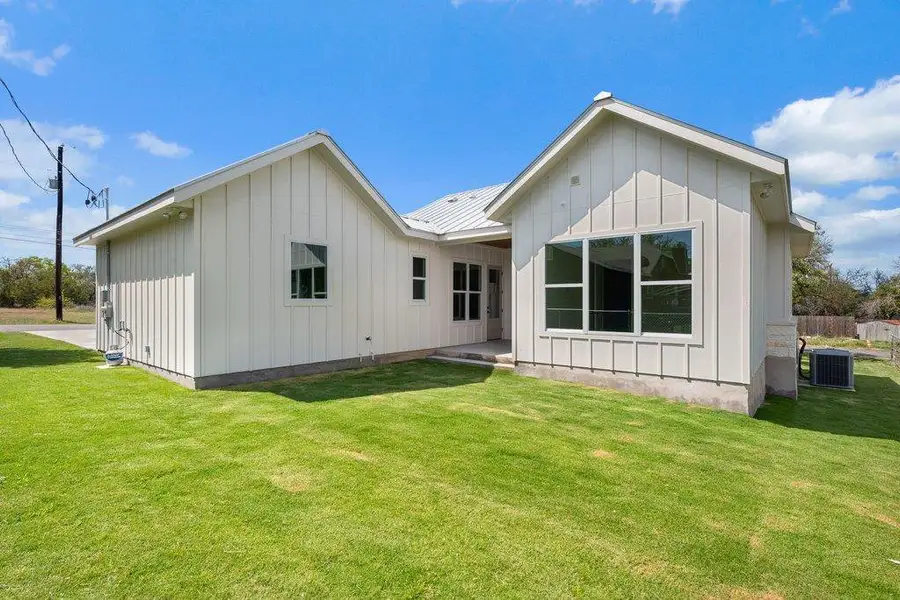The property features a well-maintained lawn and a white exterior with board and batten siding