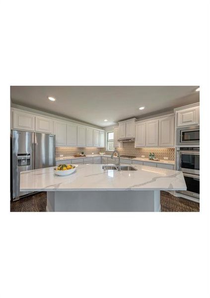 Kitchen with a center island with sink, white cabinetry, and light stone countertops