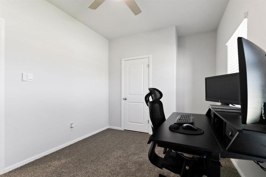 Home office featuring dark carpet and ceiling fan
