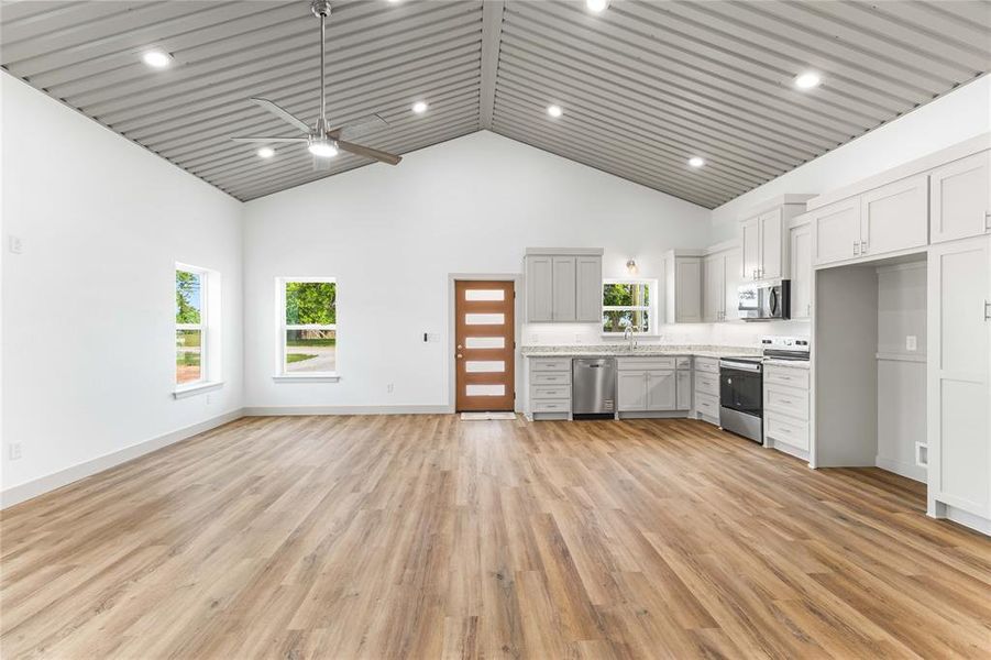 Kitchen with appliances with stainless steel finishes, high vaulted ceiling, a sink, ceiling fan, and open floor plan Kitchen with appliances with stainless steel finishes, high vaulted ceiling, a sink, ceiling fan, and open floor plan