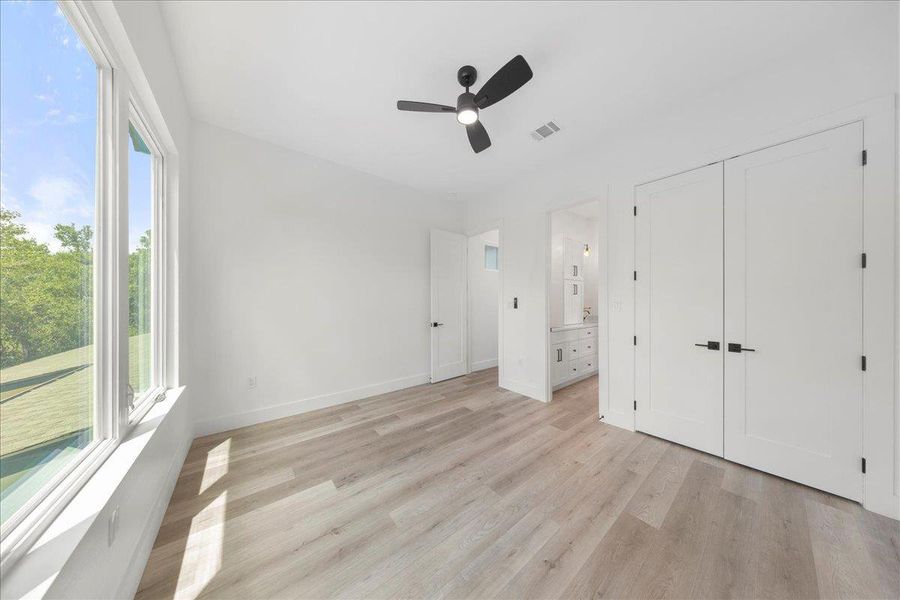 Unfurnished bedroom with light wood-style floors, ensuite bath, and ceiling fan Unfurnished bedroom with light wood-style floors, ensuite bath, and ceiling fan