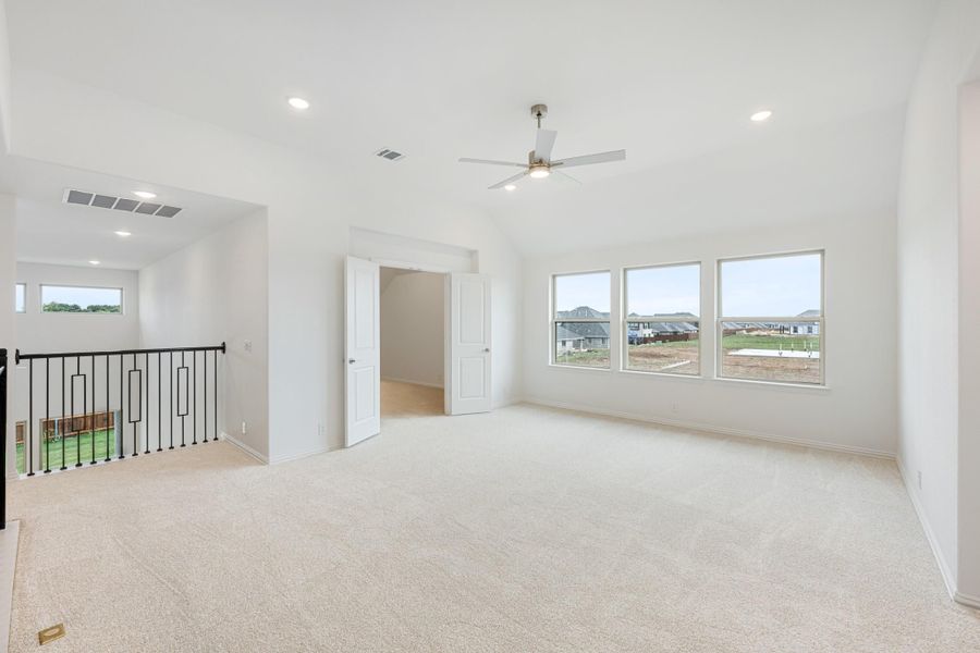 Spacious upstairs bonus room with carpet, ceiling fan, vaulted ceiling, and large windows overlooking neighborhood Spacious upstairs bonus room with carpet, ceiling fan, vaulted ceiling, and large windows overlooking neighborhood