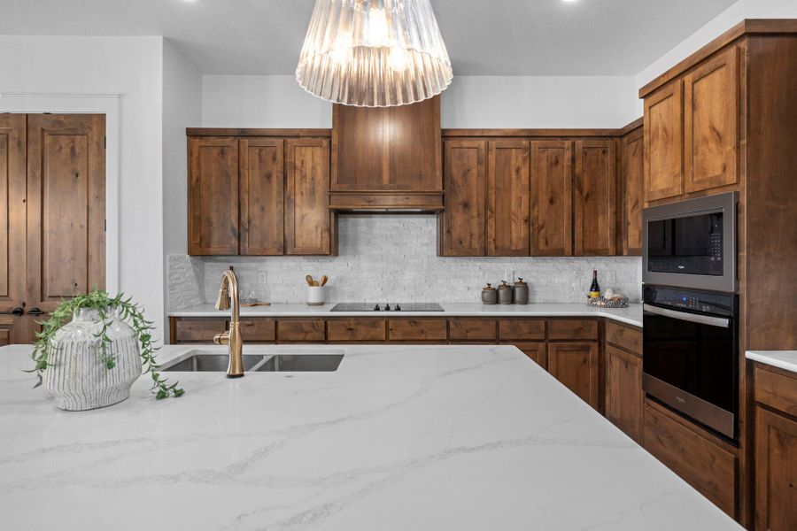 Kitchen featuring stainless steel appliances, light stone countertops, and backsplash