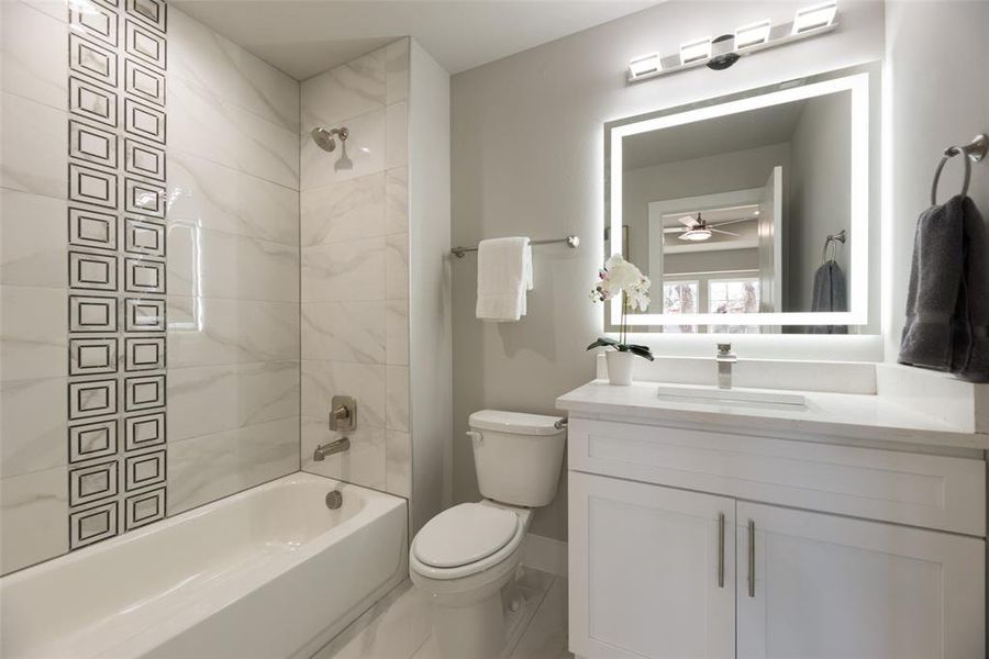 Full bathroom featuring tiled shower / bath combo, tile patterned flooring, toilet, vanity, and ceiling fan