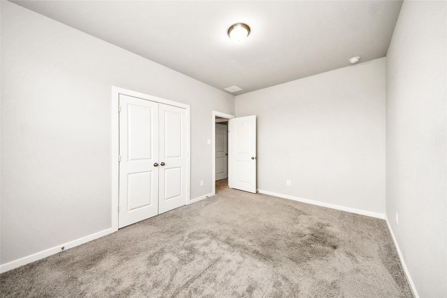 Another view of the secondary bedroom highlighting the spacious layout and cohesive modern finishes carried throughout the home.