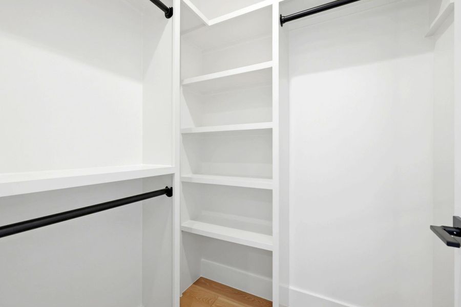 Custom white closet system featuring multiple shelving units and black hanging rods