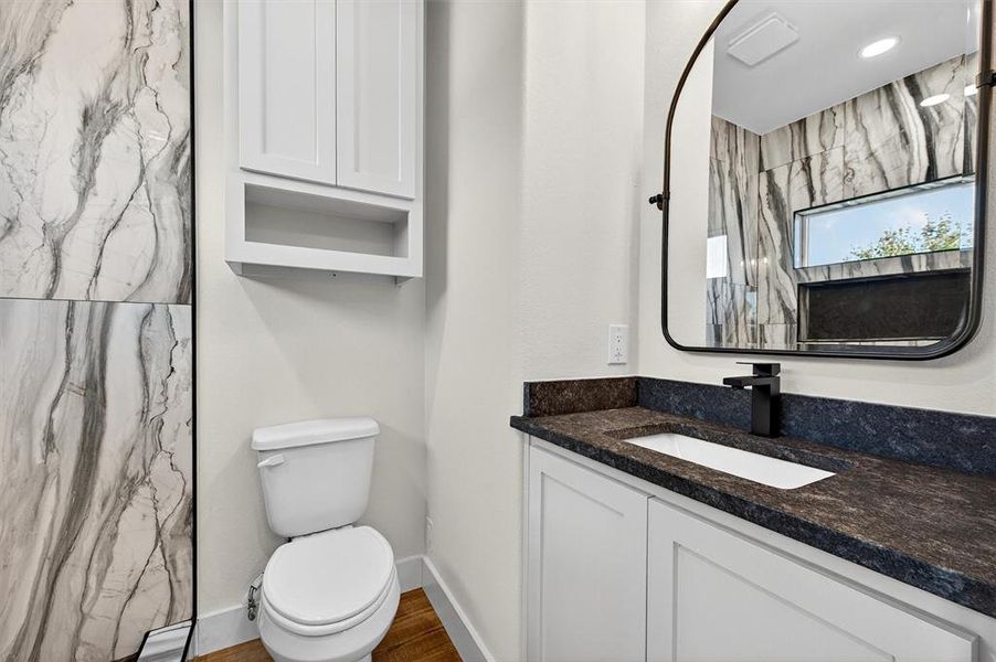 Bathroom featuring vanity, a marble finish shower, and dark wood-style flooring