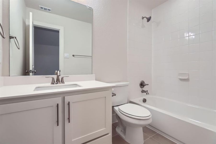 Full bathroom featuring toilet, tile patterned flooring, vanity, and tiled shower / bath