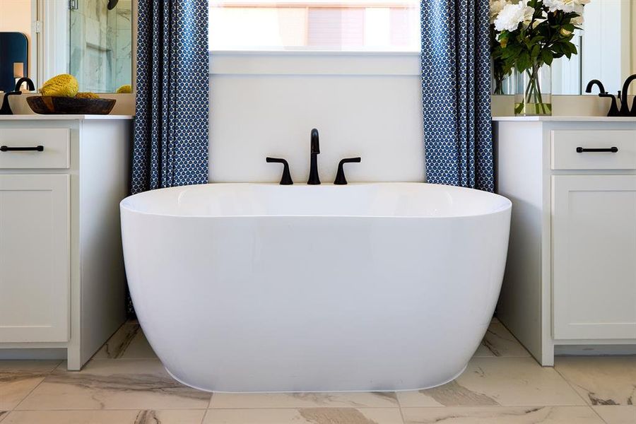 Full bathroom featuring light marble finish floors and a soaking tub