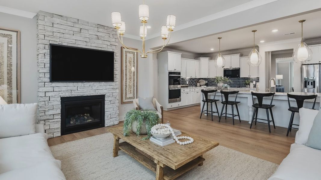 Stonefield home plan open concept family room with stone fireplace and lots of windows Stonefield home plan open concept family room with stone fireplace and lots of windows
