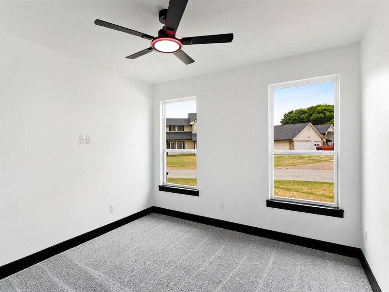 Room with white painted walls, gray patterned carpet, and black trim
