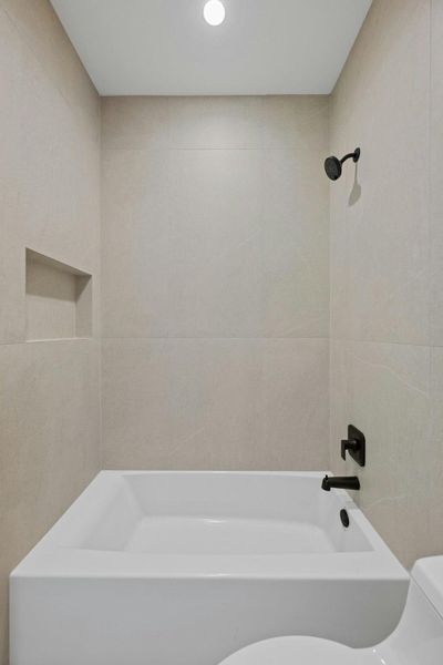 Full bath with shower / bathtub combination and tile walls