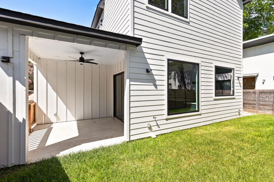 A private backyard oasis with a covered patio and verdant lawn.