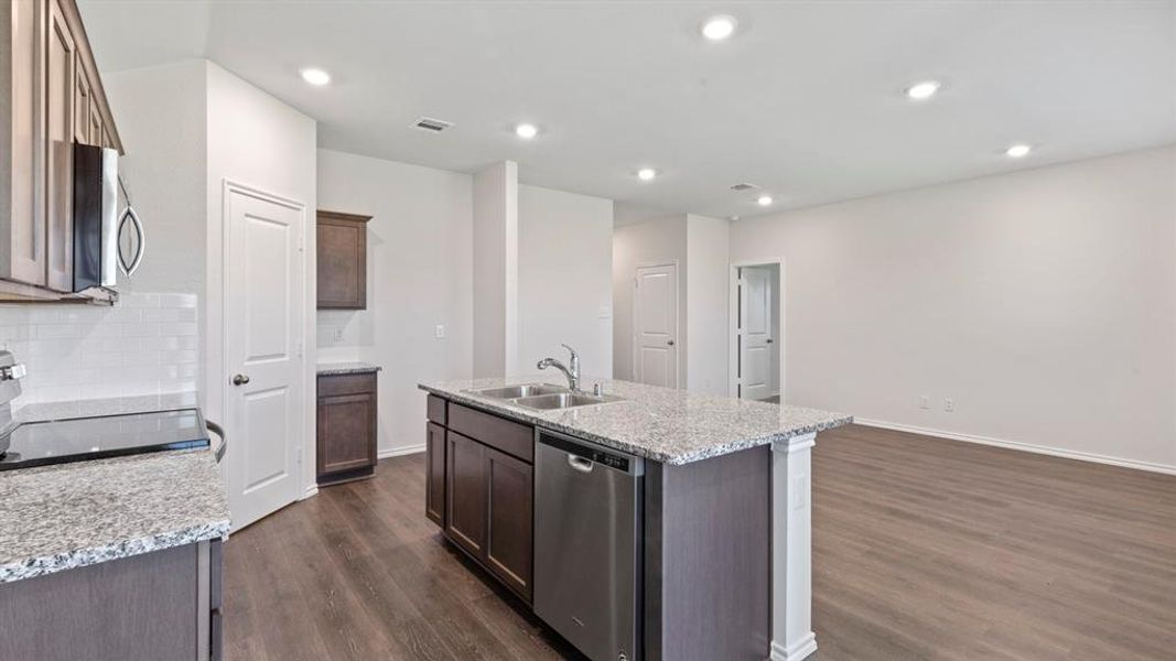 Kitchen island featuring a double-basin sink, stainless steel dishwasher, and granite countertop