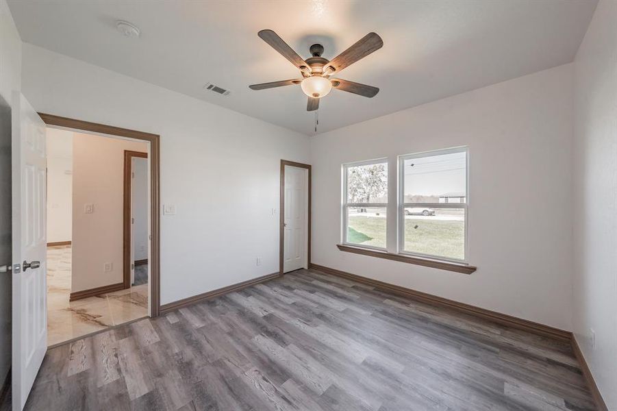 Spare room with light wood finished floors, baseboards, visible vents, and a ceiling fan