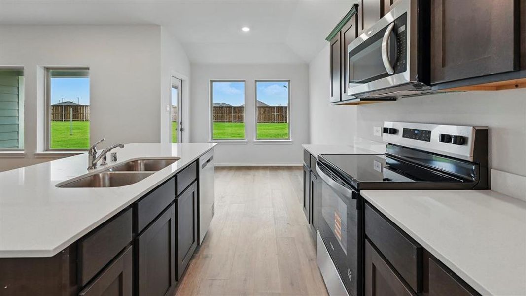 Kitchen with stainless steel appliances, a center island with sink, light wood-style flooring, light stone countertops, and recessed lighting