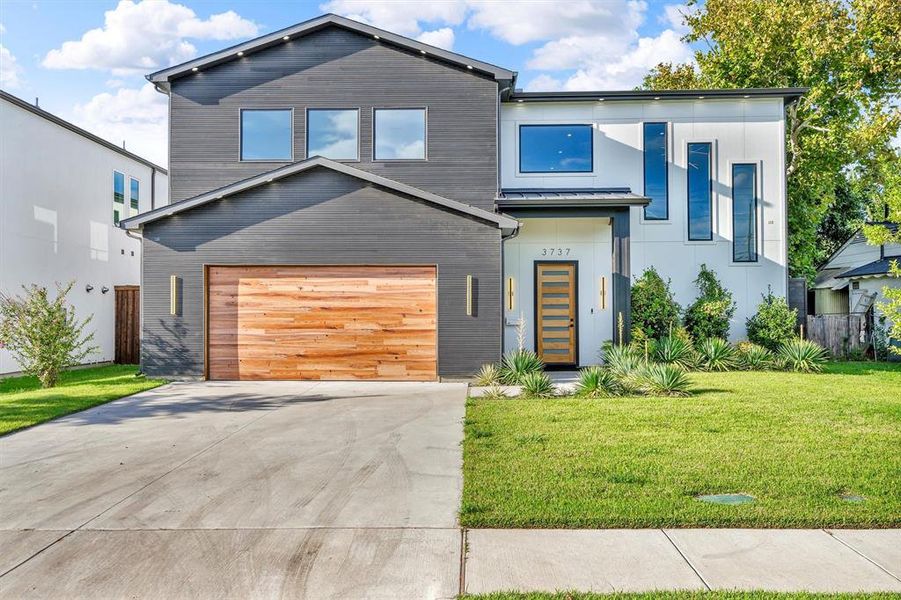Modern home featuring driveway, an attached garage, and a metal roof Modern home featuring driveway, an attached garage, and a metal roof
