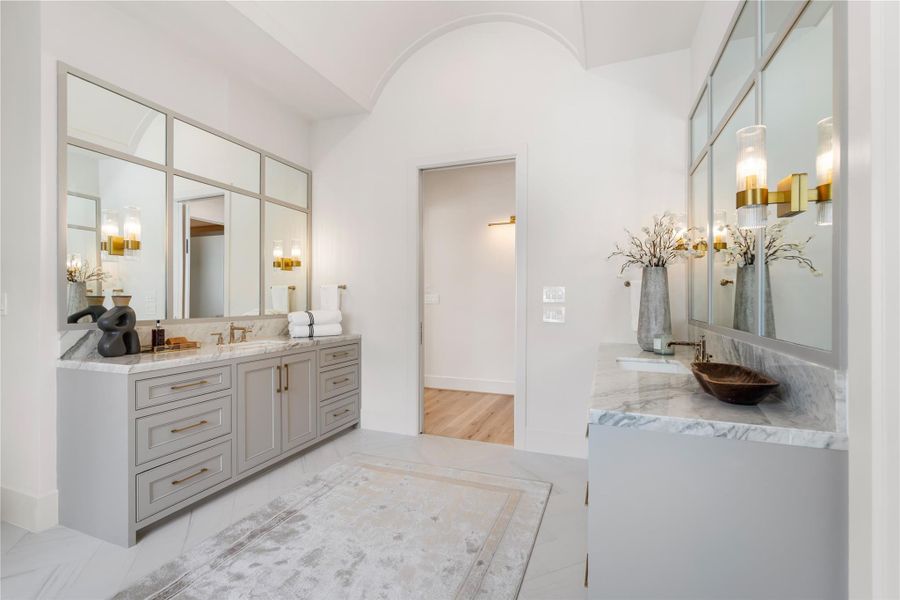 Double vanities feature sinks and an array of storage space. Huge mirrors will make primping easy! Light cabinetry brings in the tones from the marble countertops for aesthetic cohesion, and the barrel ceiling centers the elongated space.