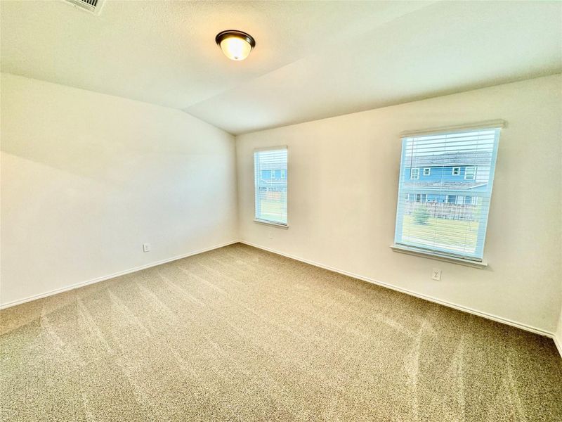 Spare room with vaulted ceiling, carpet flooring, and a textured ceiling