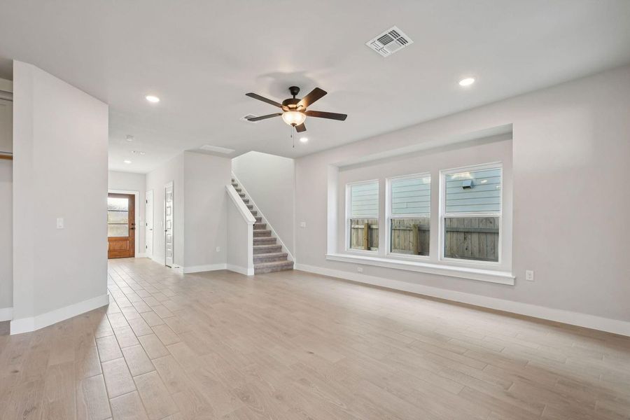 Unfurnished living room with recessed lighting, stairway, light wood-style flooring, and ceiling fan