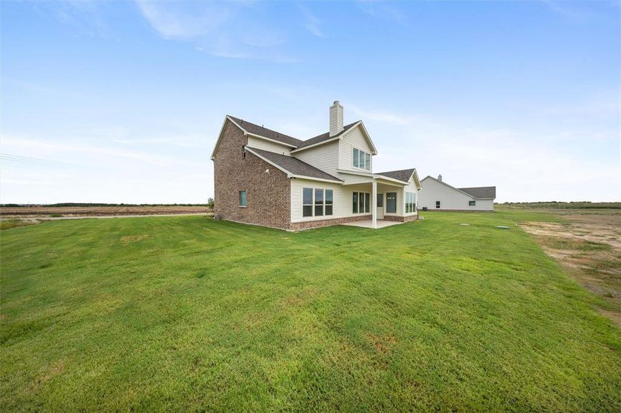 Rear view of property with a patio area, a chimney, a shingled roof, and a yard Rear view of property with a patio area, a chimney, a shingled roof, and a yard