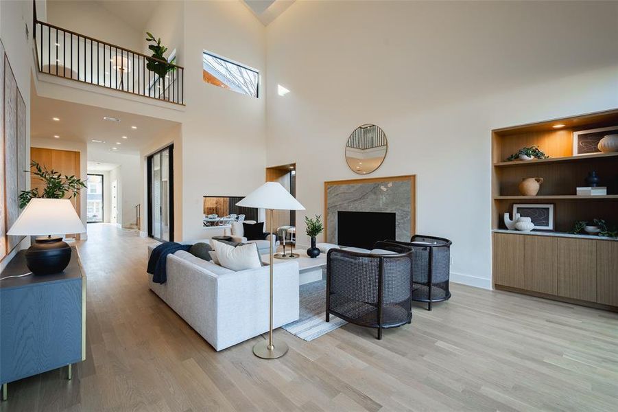 Living room featuring a fireplace, a high ceiling, and light wood-type flooring