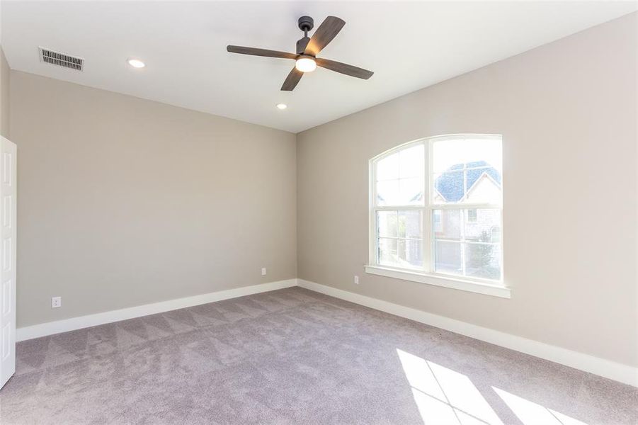 Empty room featuring ceiling fan and light carpet