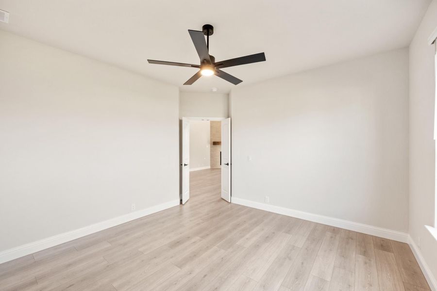 Empty bedroom with light wood floors, white walls, and a black ceiling fan with light Empty bedroom with light wood floors, white walls, and a black ceiling fan with light