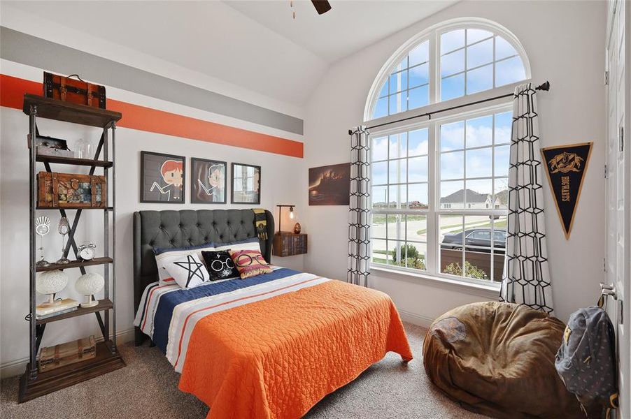 Carpeted bedroom with lofted ceiling, multiple windows, and ceiling fan